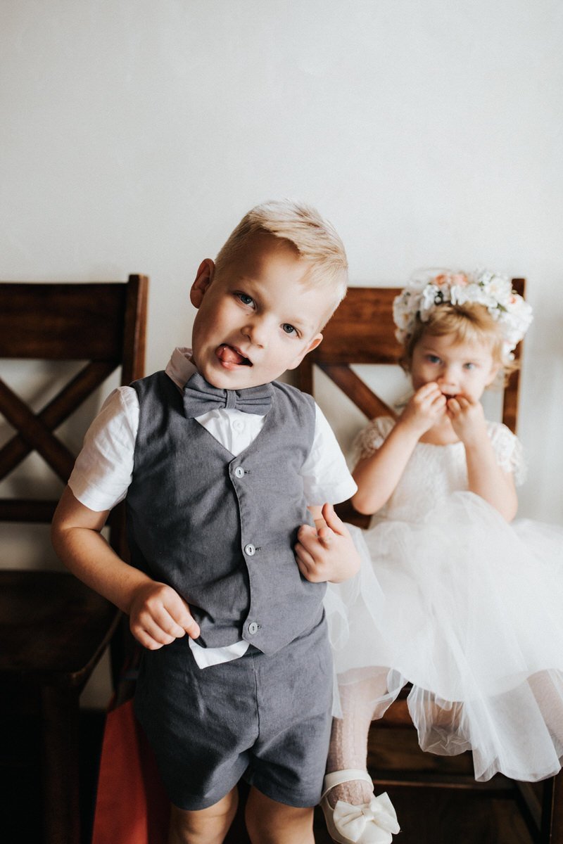 A flower girl and ring bearer make funny faces at the camera.